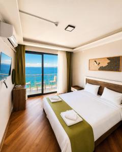 a bedroom with a large bed with a view of the ocean at Pavlonya Garden in İntepe