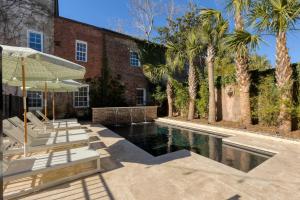 a pool with lounge chairs and a building with palm trees at The Nicholas Veranda King Suite - Steps to King in Charleston