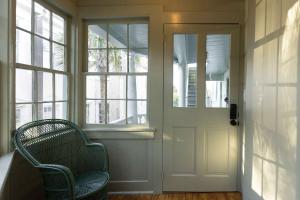 a wicker chair sitting in front of a door at The Nicholas Veranda King Suite - Steps to King in Charleston