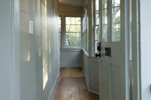 an empty hallway with windows and a wooden floor at The Nicholas Veranda King Suite - Steps to King in Charleston