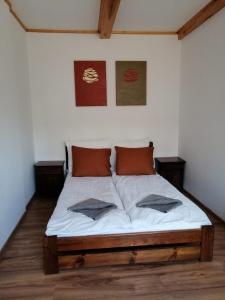 a bedroom with a bed with white sheets and orange pillows at Termalne Pokoje in Uniejow