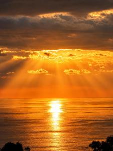 a sunset over the ocean with the sun shining at Pura Natura Lodge in Manuel Antonio