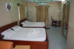 two beds in a room with a table and a chair at Link Hotel in Lokossa +6 photos
