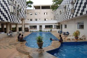 a pool in a building with people sitting around it at Link Hotel in Lokossa