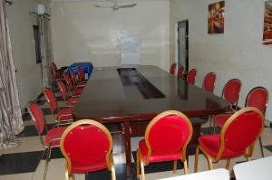 a conference room with a long table and red chairs at Link Hotel in Lokossa
