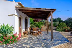 a patio with a table and chairs under a roof at Corvatos Casas do Monte in Almodôvar