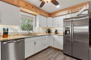 a kitchen with white cabinets and a stainless steel refrigerator at Sunshine Days OBX in Nags Head