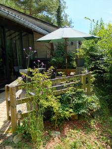 a wooden bench with an umbrella in a garden at vakantieverblijf Coo-sy in Stavelot
