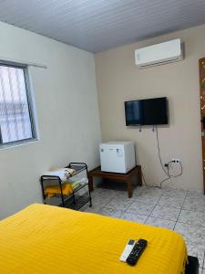 a bedroom with a yellow bed and a tv at Cantinho do Sol in Recife