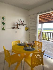 a dining room with a yellow table and chairs at Chalé Recanto da Coruja in Pão de Açúcar +12 photos