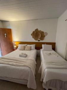 two beds in a hotel room with white sheets at Chalé Recanto da Coruja in Pão de Açúcar