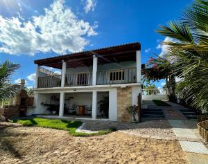 a house on the beach with palm trees at Chalé Recanto da Coruja in Pão de Açúcar