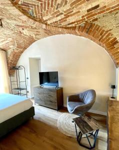 a bedroom with a bed and a tv and a chair at La Morra Relax in La Morra