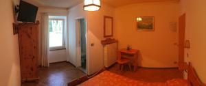 a room with a bedroom with orange walls and a window at Hotel Juventus in Auronzo di Cadore