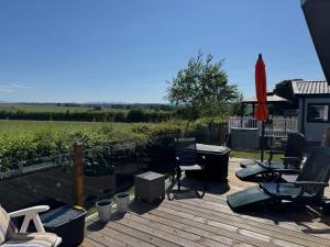 a deck with chairs and a table and an umbrella at 36 Ravens Nest large 3 bedroom lodge with views No sign written vans allowed on site in High Hesket +5 photos