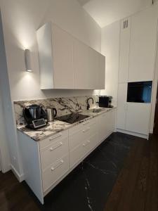 a kitchen with white cabinets and marble counter tops at Apartament Brzeg in Augustów
