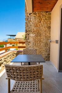 a table and chairs on a patio with a stone wall at Mylos Hotel Apartments in Platanias