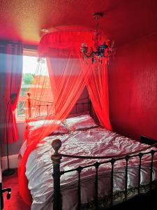 a bedroom with a bed with red curtains and a window at The Little Green Hideaway in Fivemiletown