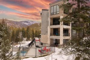 a building in the snow with red chairs in front of it at NEW Ski-In Ski-Out Romantic Studio for Two in Winter Park