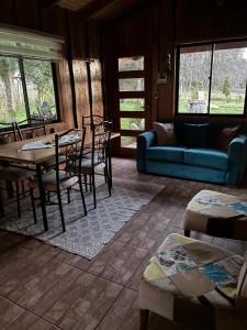a living room with a table and chairs and a couch at Cabaña Refugio Rustica in Pucón