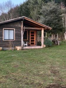 a log cabin with a porch in a yard at Cabaña Refugio Rustica in Pucón
