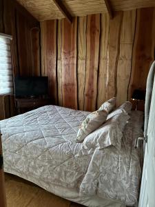 a bedroom with a bed with pillows on it at Cabaña Refugio Rustica in Pucón