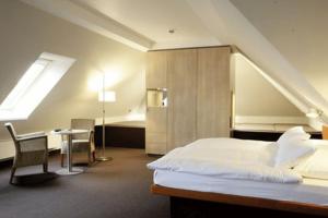 a bedroom with a bed and a desk and a window at Hotel Windschur in Sankt Peter-Ording