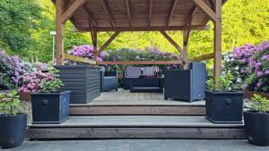 a wooden gazebo with potted plants and flowers at Wolfcenter Gästezimmer in Dörverden