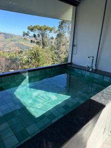 a pool with a view of the mountains through a window at Refúgio Deusmideu in São Bento do Sapucaí