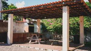 a wooden pergola with a picnic table and a bench at Cabañas de Asgard in Nueva Gorgona