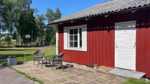 a red and white shed with two chairs and a table at Glaskogen Holiday Homes in Glava