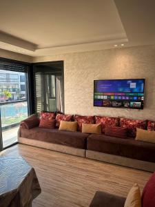 a large couch in a living room with a flat screen tv at Relaxing residence oceanic Sidi rhal in Sidi Rahal