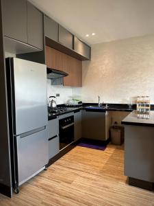 a kitchen with stainless steel appliances and wooden cabinets at Relaxing residence oceanic Sidi rhal in Sidi Rahal