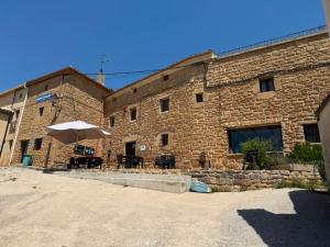 a large brick building with an umbrella and tables at Albergue OasisTrails for pilgrims on Camino de Santiago in Villamayor de Monjardín