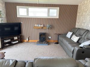 a living room with a couch and a flat screen tv at Retreat to the Chalet in Withernsea