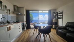 a kitchen and living room with a table and a couch at Casa do Brasileiro in Arco da Calheta