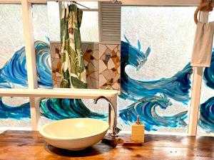 a bathroom with a sink and a wave shower curtain at Franky's Fare in Fare