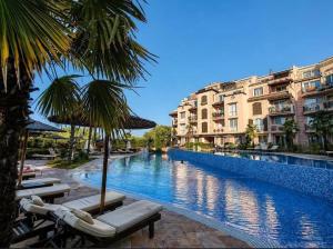 a swimming pool with chairs and umbrellas next to buildings at Студио Морски бриз in Sozopol
