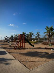 a playground with a slide in a park with palm trees at Relaxing residence oceanic Sidi rhal in Sidi Rahal
