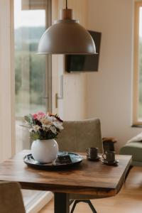 a table with a vase of flowers and two cups at Natururlaub by Klotz TINY HAUS a in Überlingen