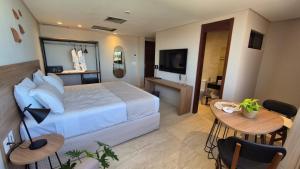 a bedroom with a bed and a table and a television at Niníve Boutique Hotel in Cabedelo