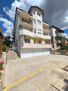 a large white building with a garage in a parking lot at White House Apartments - Forest in Haskovo