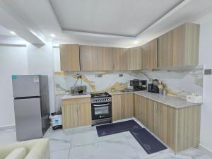 a kitchen with wooden cabinets and a stainless steel refrigerator at Marie's 2bed all-ensuite Tuffoam 310 in Kisumu +6 photos