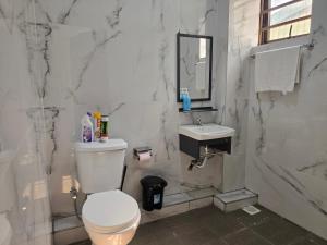 a white bathroom with a toilet and a sink at Marie's 2bed all-ensuite Tuffoam 310 in Kisumu
