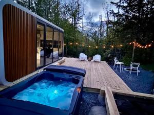 a hot tub on a deck next to a house at Romantic tiny Pod for Two HotTub Pond FirePit in Haines Falls