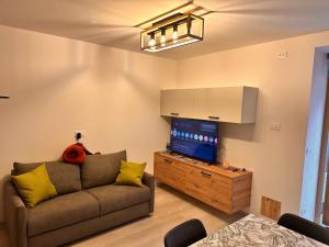 a living room with a couch and a flat screen tv at Casa D'Ambros - Cadore in Santo Stefano di Cadore