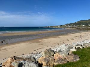 a beach with rocks and the ocean with people on it at High Road Cottage in Dooagh