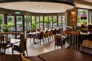 a restaurant with tables and chairs and windows at Hotel Hof van Gelre by Flow in Lochem