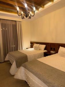 a hotel room with two beds and a chandelier at HOTEL POSADA DE LA MONEDA in Zacatecas