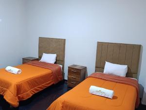 two beds with orange sheets in a room at HOTEL BOUTIQUE TerrazaINN in Arequipa